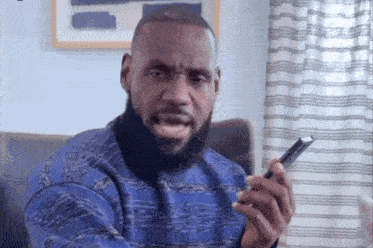 a man with a beard is holding a cell phone in his hand and making a funny face .
