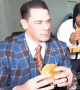 a man in a suit and tie is eating a sandwich while sitting at a table .