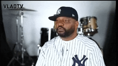 a man wearing a new york yankees baseball uniform is sitting in front of drums