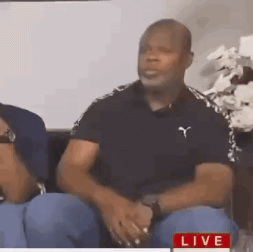 a man in a black shirt is sitting on a couch with a woman .