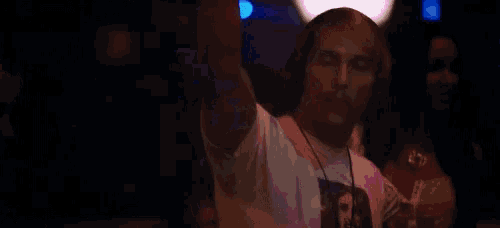 a man wearing headphones is dancing in a club with a woman in the background .