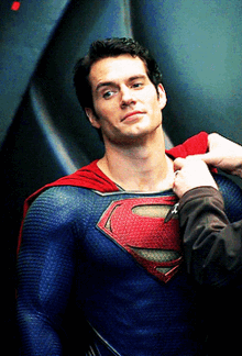 a man in a superman costume is being helped by another man