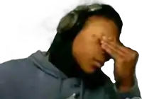 a person wearing headphones is covering their face with their hands .