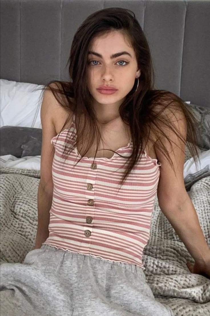 This may contain: a young woman sitting on top of a bed