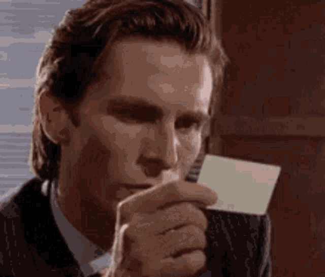 a man in a suit and tie is holding a business card in his hand .