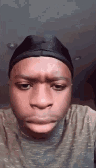 a young man wearing a black hat and a t-shirt is making a funny face .