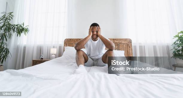 stressed-overslept-african-american-man-sitting-in-bed-at-home.jpg