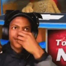a man wearing headphones covering his nose in front of a sign that says  to 