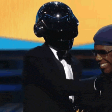 a man wearing a black helmet and a tuxedo stands next to another man