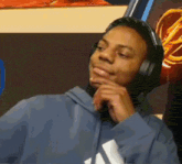a man wearing headphones and a blue hoodie with the word adidas on the front