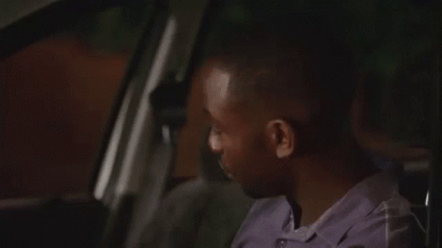 a man is sitting in the back seat of a car making a funny face .
