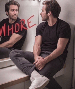 a man is sitting in front of a mirror with whore written on it