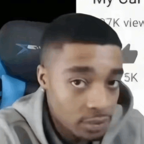 a close up of a man 's face with a thumbs up in the background