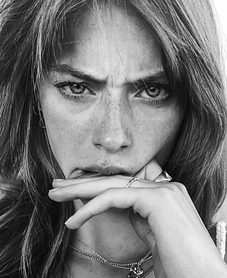 This may contain: a black and white photo of a woman with freckled hair holding her hand to her mouth