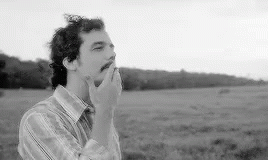 a man is smoking a cigarette in a field .