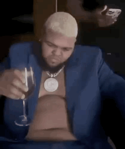 a man in a blue suit is holding a wine glass .