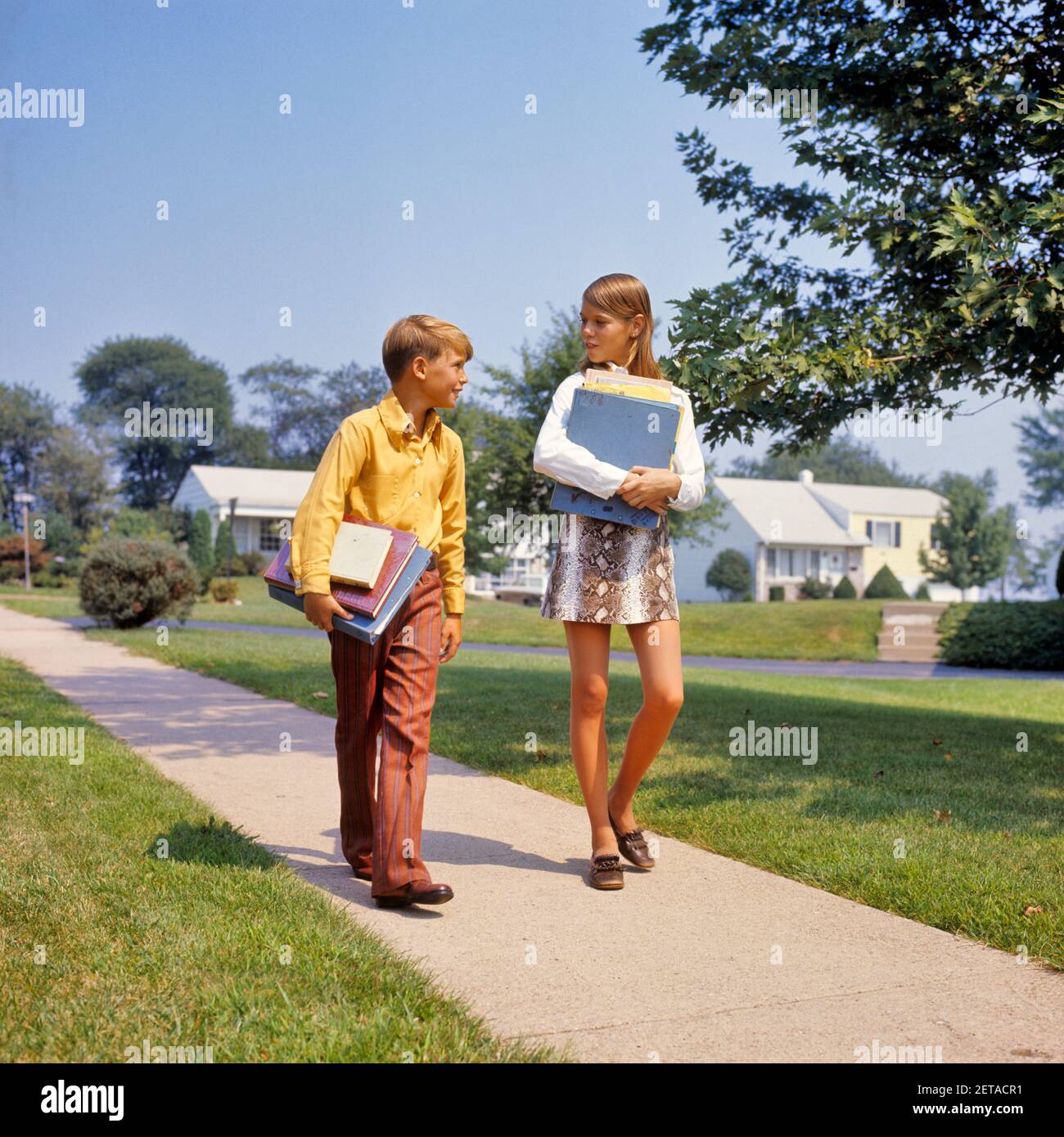 1960s-1970s-boy-girl-on-sidewalk-walking-home-from-or-to-school-talking-carrying-books-girl-wearing-faux-snakeskin-mini-skirt-ks7526-har001-hars-1-juvenile-elementary-style-communication-friend-mini-joy-lifestyle-females-houses-brothers-healthiness-home-life-copy-space-friendship-full-length-residential-males-buildings-siblings-sisters-schools-grade-happiness-neighborhood-homes-primary-sibling-connection-faux-friendly-residence-stylish-or-cooperation-grade-school-growth-juveniles-middle-school-miniskirt-pre-teen-pre-teen-girl-togetherness-caucasian-ethnicity-har001-old-fashioned-2ETACR1.jpg