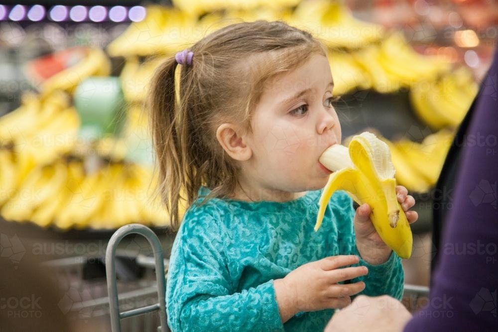 little-girl-in-shopping-trolley-eating-a-banana-austockphoto-000020429.jpg