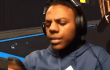 a man wearing headphones and a hoodie looks at his phone