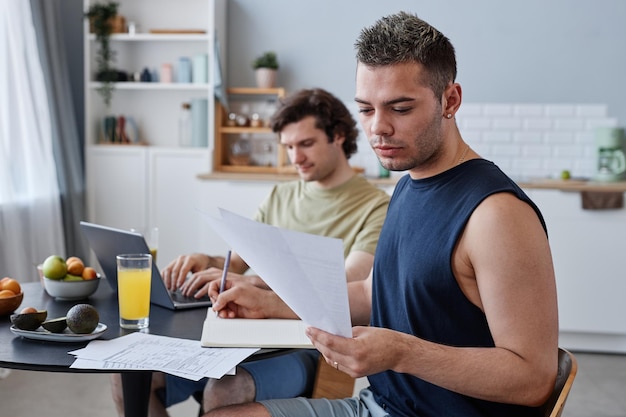 portrait-young-gay-couple-living-together-with-focus-man-studying-kitchen-table_236854-46029.jpg