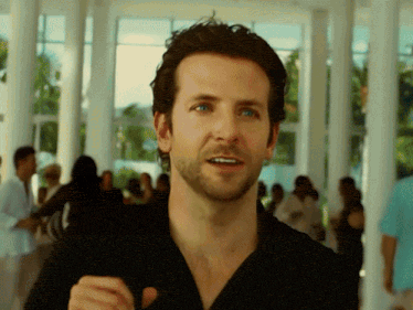 a man with a beard wearing a black shirt stands in front of a crowd