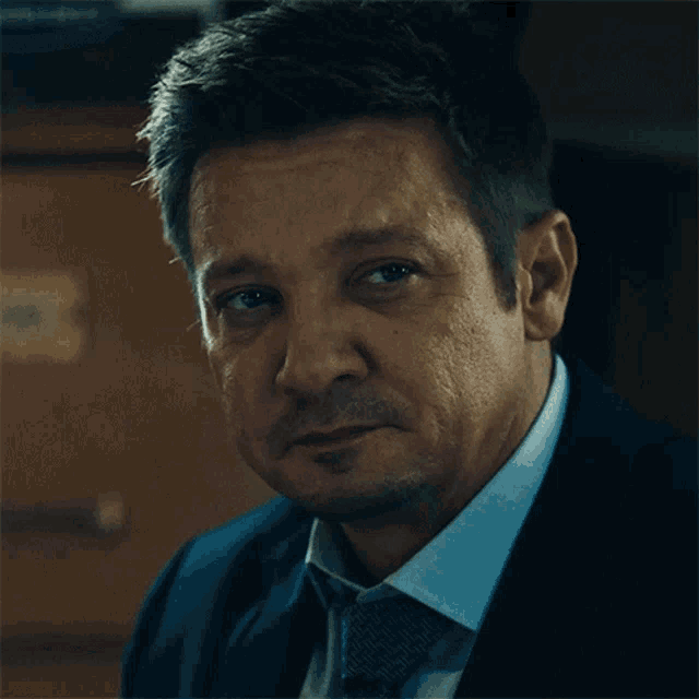 a man in a suit and tie looks at the camera with a serious look on his face