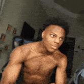 a shirtless man is sitting in a chair in front of a wall with wanted posters