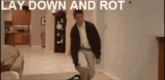 a man is kneeling down in a living room with the words  lay down and rot  above him