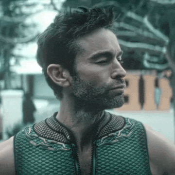 a man with a beard is wearing a green vest and looking to the side .