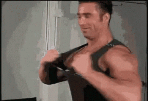 a muscular man is wearing a black tank top and a black bra .