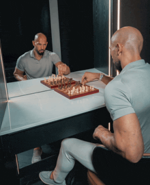 a man playing chess with his reflection in the mirror