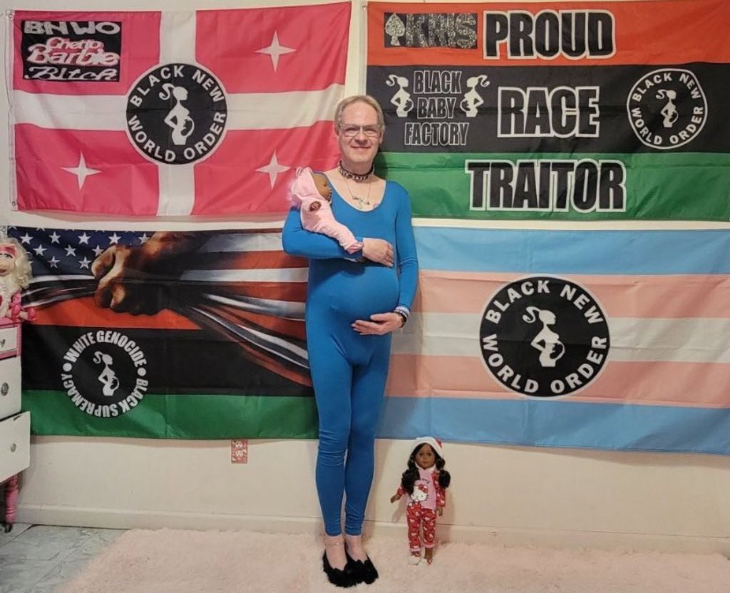 Oli London on X: White transgender man who identities as a black woman  shows off his 'pregnancy' bump as he holds a black newborn baby doll in his  arms. Flags behind him