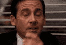 a close up of a man 's face with his eyes closed and his hand on his chin .