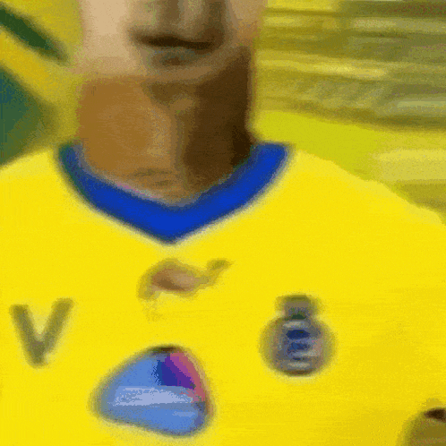 a blurry picture of a person wearing a yellow shirt with the letter v on it