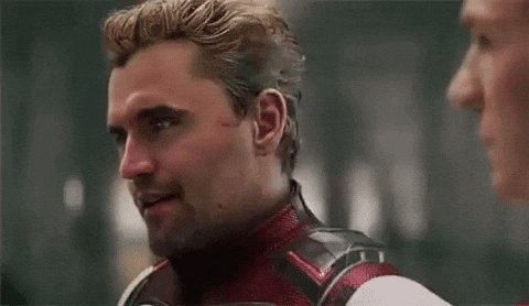 a man in a superhero costume is talking to another man in a room .