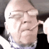 a man wearing glasses and a bandana is smoking a cigarette