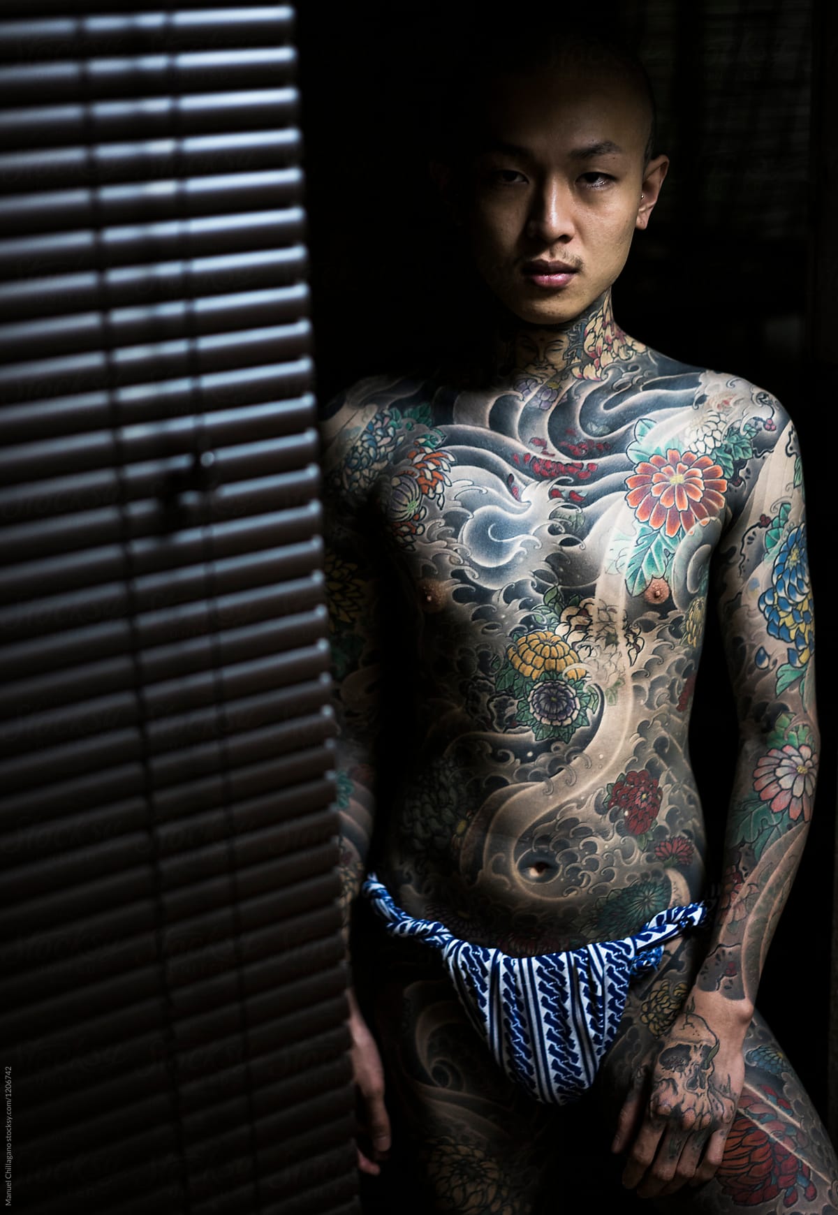 Japanese male in a tattoo studio exposing his tattooed body by Manuel  Chillagano - Stocksy United