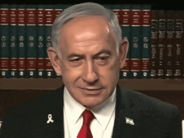 a man in a suit and tie with a red ribbon on his shirt