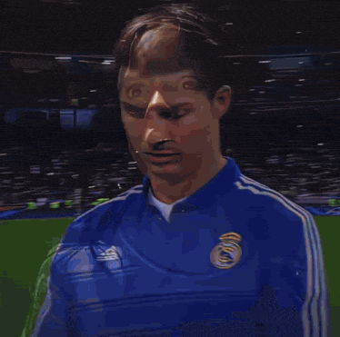 a soccer player wearing a blue adidas jacket smiles