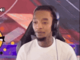 a man wearing headphones is sitting in a chair and looking at the camera .