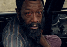 a man with red eyes and a beard looks at the camera