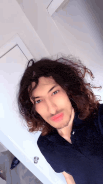 a man with long curly hair and a beard is taking a picture of himself