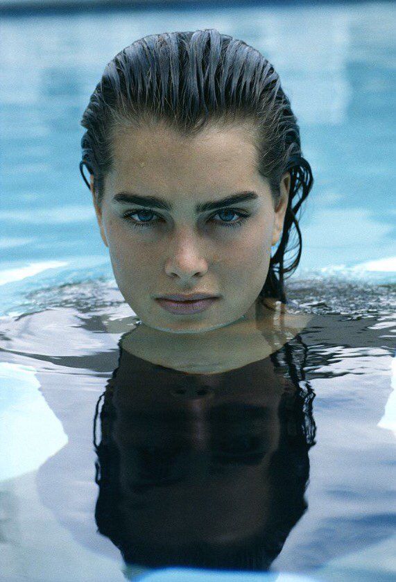 This may contain: a young woman swimming in a pool with her head above the water
