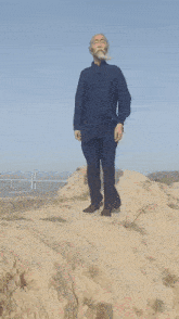 a man with a beard is standing on a sand dune