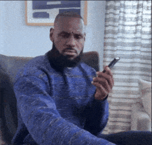 a man wearing a blue sweater is sitting in a chair holding a cell phone