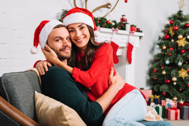 happy-couple-christmas-hats-embracing-sofa_23-2147951073.jpg