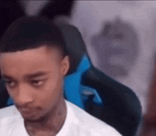 a young man is sitting in a gaming chair looking at the camera .