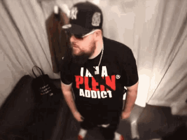 a man wearing a black shirt that says  i am a plein addict 