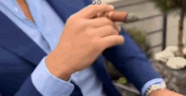 a man in a suit is smoking a cigar while wearing a watch .