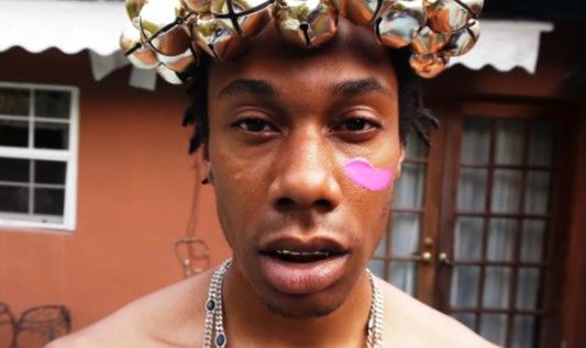 This may contain: a shirtless man with pink nose ring and flower crown on top of his head